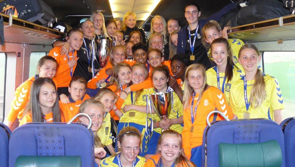 Brøndbys U14- og U16-pigerne viser pokaler og medaljer frem i toget hjem fra Gøteborg.